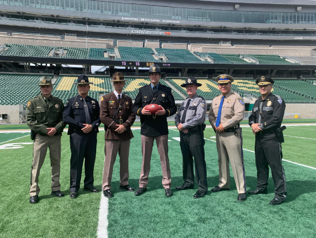 Chief Packard (center) of CSP is joined by other regional law enforcement agencies at Canvas Stadium to promote a traffic safety message at the upcoming Border War game