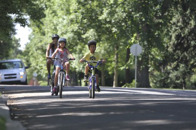 A mother and her two children ride their bikes along a tree-lined neighborhood street. Photo courtesy of Bicycle Colorado. 