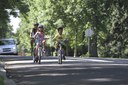 The photograph shows a mother and her two children bicycling along a quiet neighborhood street lined with trees. Photo courtesy of Bicycle Colorado. thumbnail image
