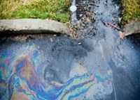 Oil, gas, or unknown substances with an oil sheen entering a storm drain inlet