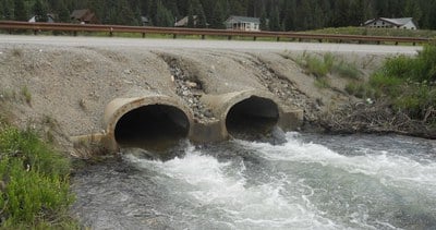 Two concrete culverts conveying a stream under a highway.