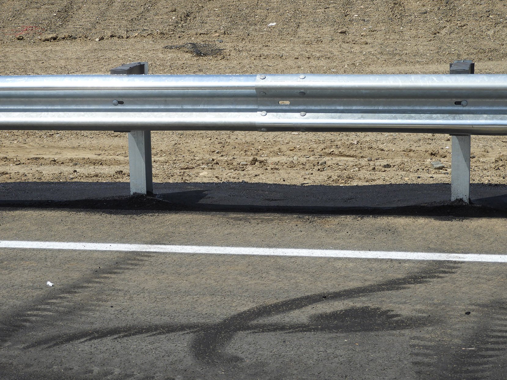 Asphalt around guardrail posts, south of 144th Avenue on the west side of southbound I-25