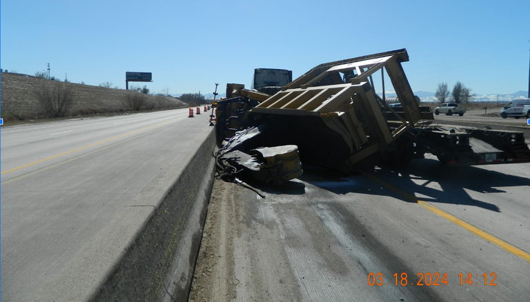 The tractor-trailer, towing construction equipment, on its side after hitting the bridge, picture taken on March 18, 2023