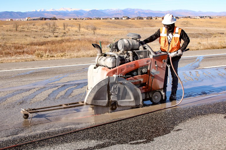 Construction worker cutting asphalt