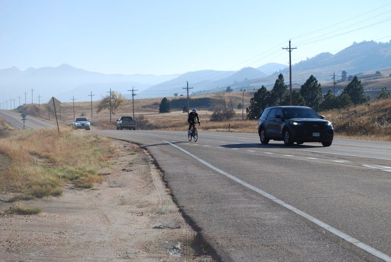 An image of a bicyclist riding next to a car.