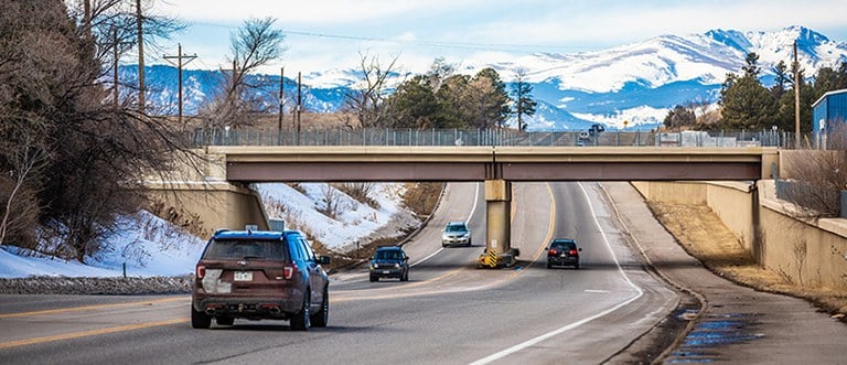 Image of cars driving under railroad bridge on Colorado State Highway 7 (CO 7) in Boulder County, Colorado.