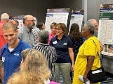 A crowd conversing in the middle of a room during Public Meeting