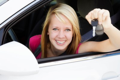 Teen driver holding a set of keys behind the wheel of a car