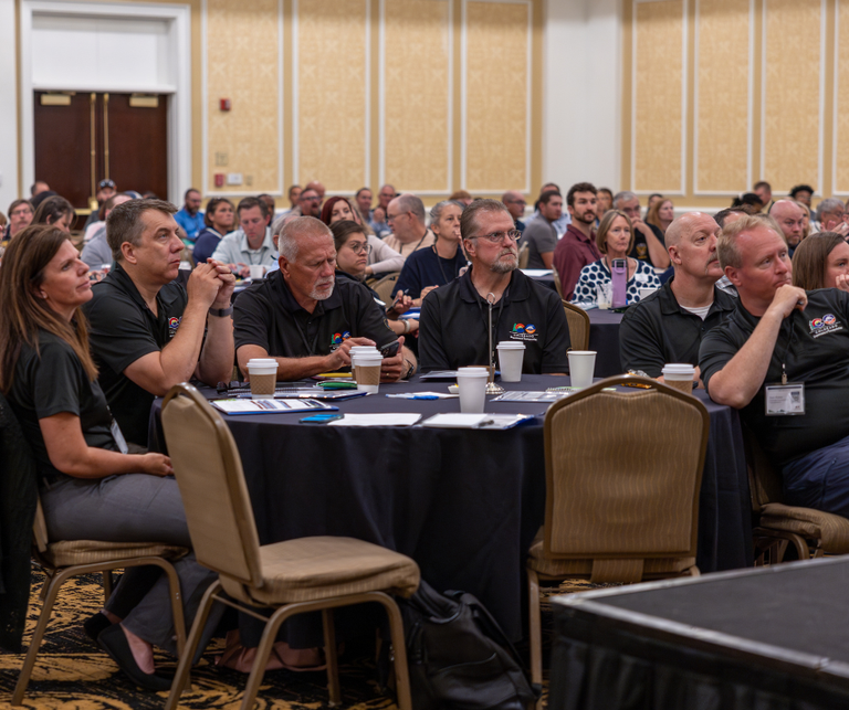 Large group of Colorado Traffic Safety Summit attendees sitting around black tables in a large conference room at the Antlers Hotel.