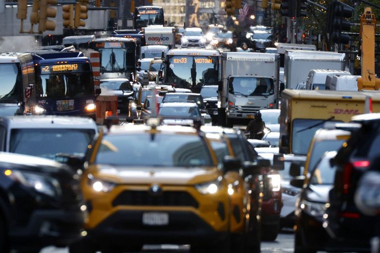 Cars, buses and trucks stopped in heavy traffic in a downtown area.