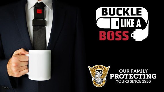 A man holding a coffee mug. The man is wearing a suit and a tie that looks like a seat belt. Text overlay next to him reads, "buckle like a boss." The Colorado State Patrol logo is under the text. Text overlay next to the logo reads, "our family protecting yours since 1935."