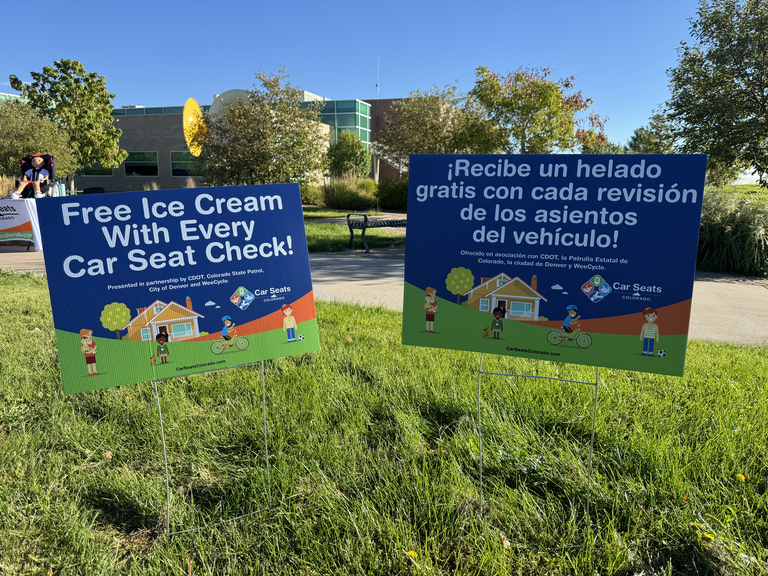 Two yard signs, one in English and one in Spanish inviting people to get free ice cream with their car seat checks.