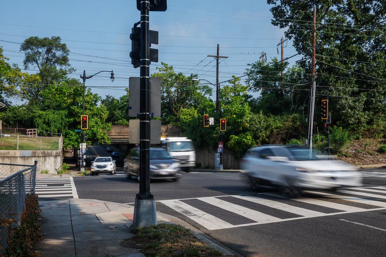 City street in Washington, D.C. with several cars driving through a traffic light. 