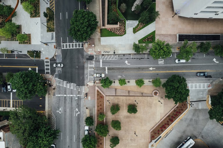 Aerial view of city streets with cars, sidewalks, buildings and trees.